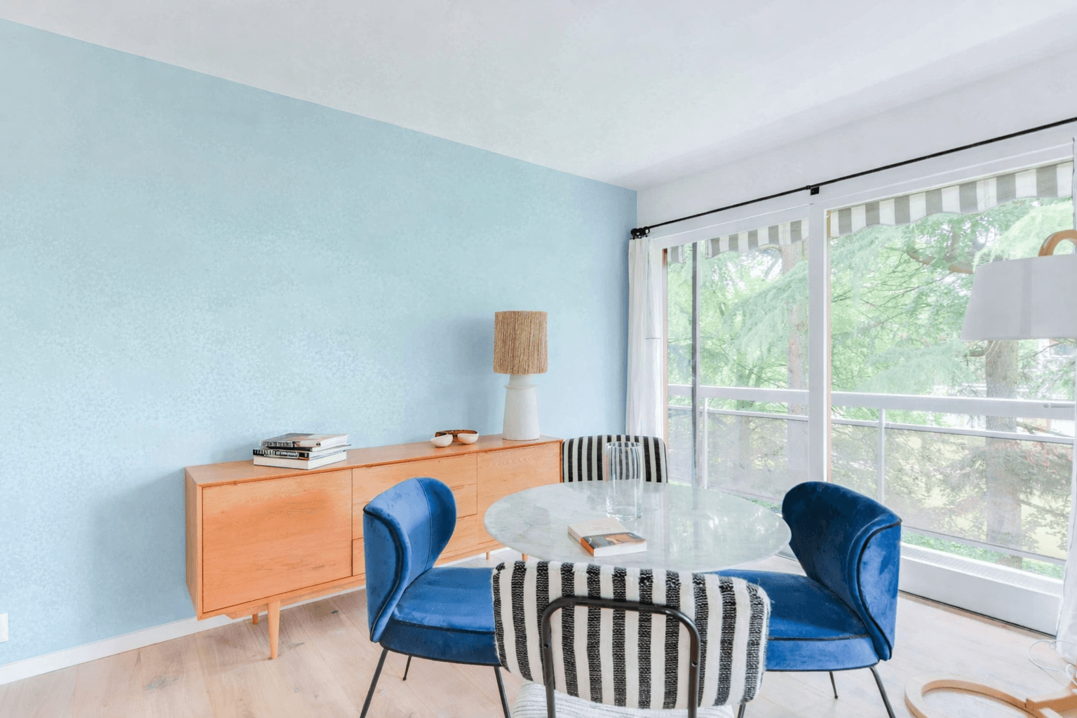 Same dining area with the mural replaced by a plain light blue wall after AI interior design
